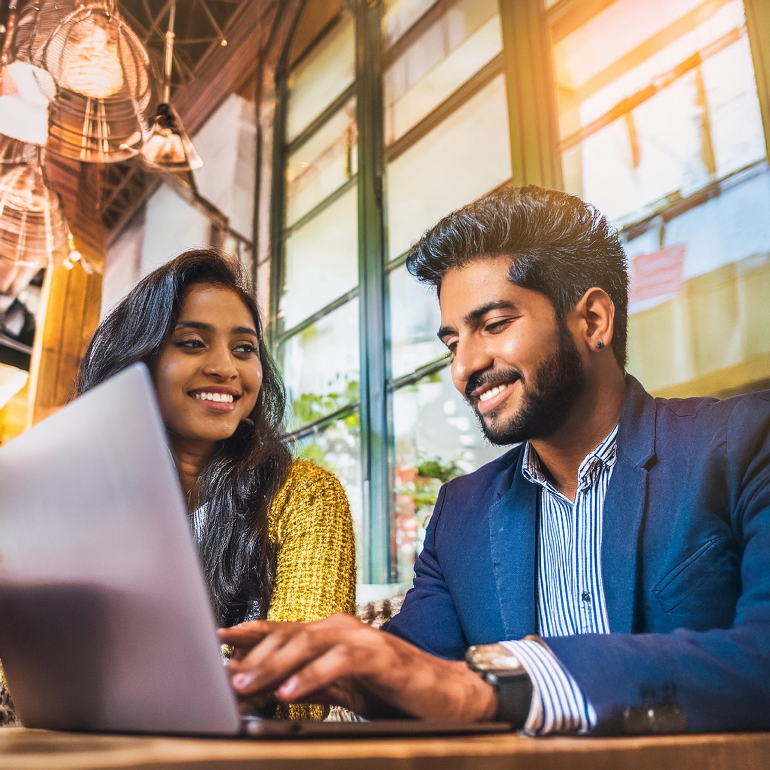A stylish couple working on their laptops and enjoying premium coffee in a chic cafe.